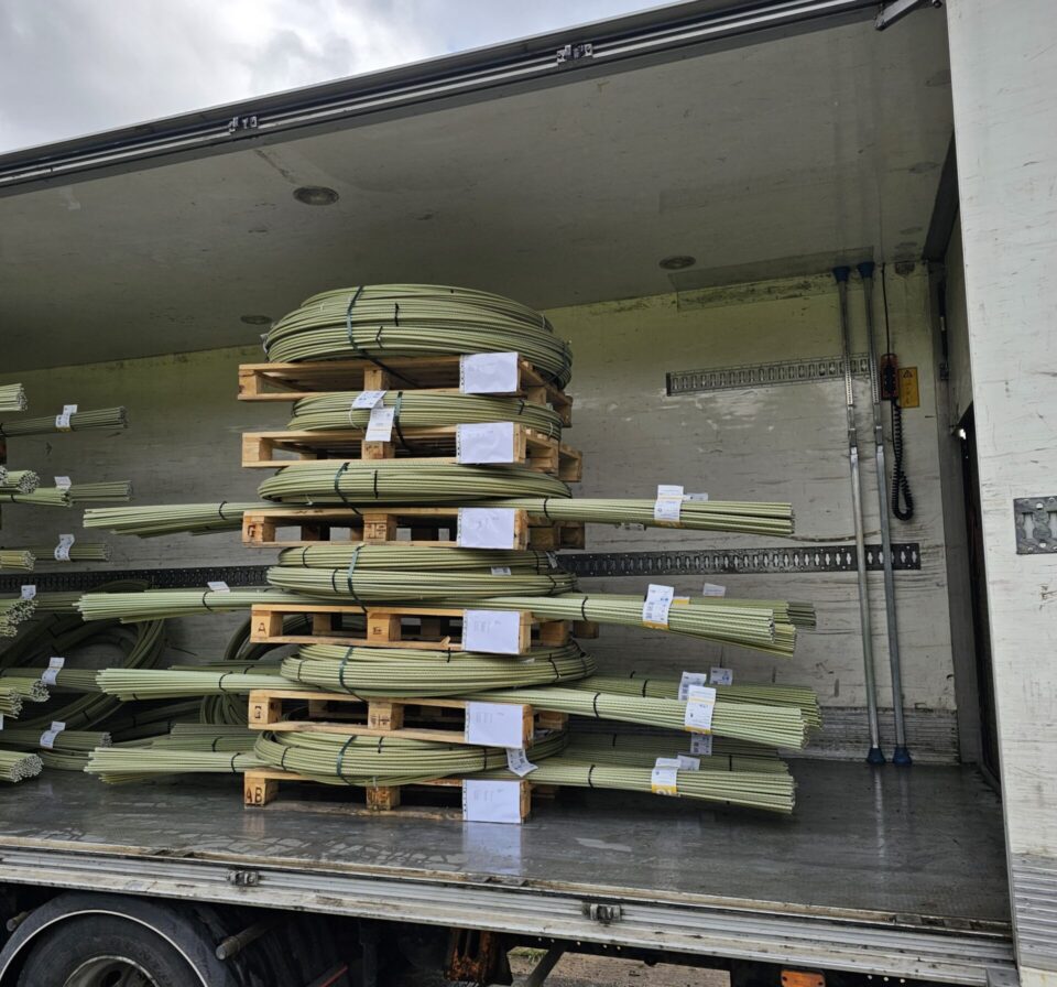 Palletised GFRP composite rebar coils and straight bars on a truck, corrosion-resistant reinforcement for concrete slabs, roads, and infrastructure.