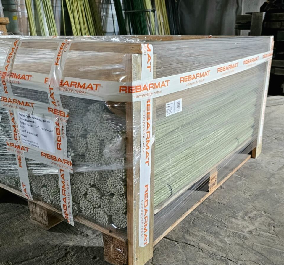 Palletized REBARMAT® GFRP composite rebars securely wrapped in protective film and branded tape, prepared for shipment from production facility. Fiberglass reinforcement bars stacked on wooden pallets demonstrate controlled packaging and ready-to-deliver construction materials.