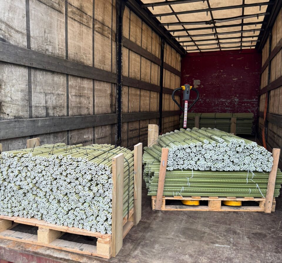 Palletized GFRP composite rebars secured inside a truck trailer, prepared for international delivery. Bundled fiberglass reinforcement bars are stacked on wooden pallets, demonstrating organized logistics and ready-to-ship construction materials.